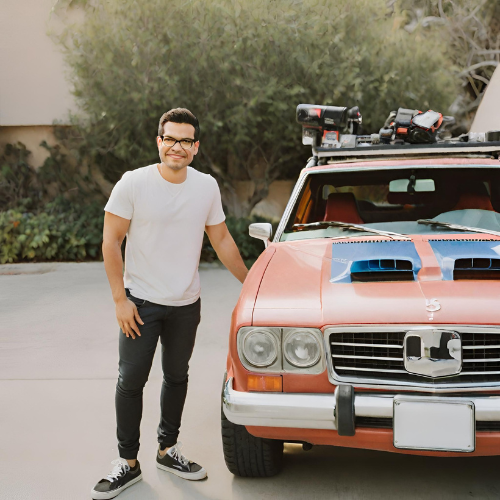 Tai Lopez standing next to his luxury vehicle, showcasing his success and wealth.